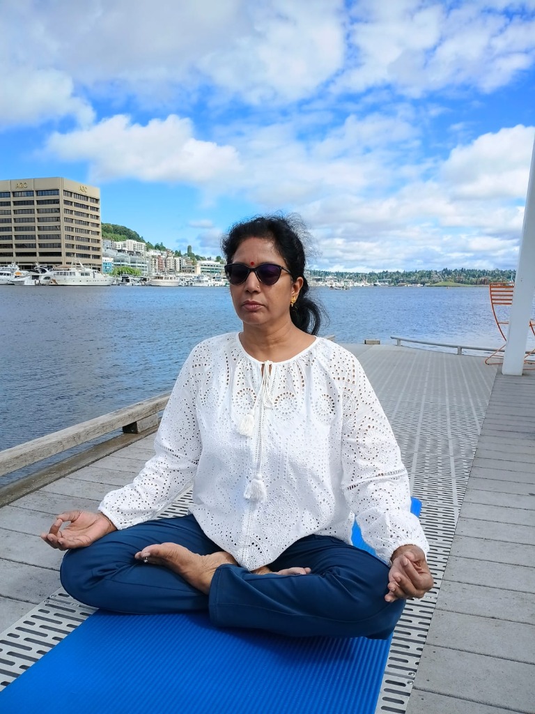 Dr. Seema Saxena meditating in Padmasana posture on a dock by the lake